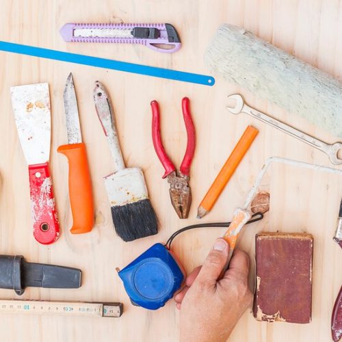 old-construction-hand-tool-set-with-worker-hand-white-wooden-background_1150-6089